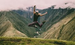 woman jumping on green mountains
