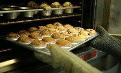 person holds tray of muffins on tray