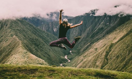 woman jumping on green mountains