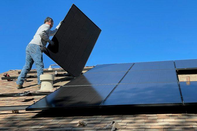 man in white dress shirt and blue denim jeans sitting on white and black solar panel